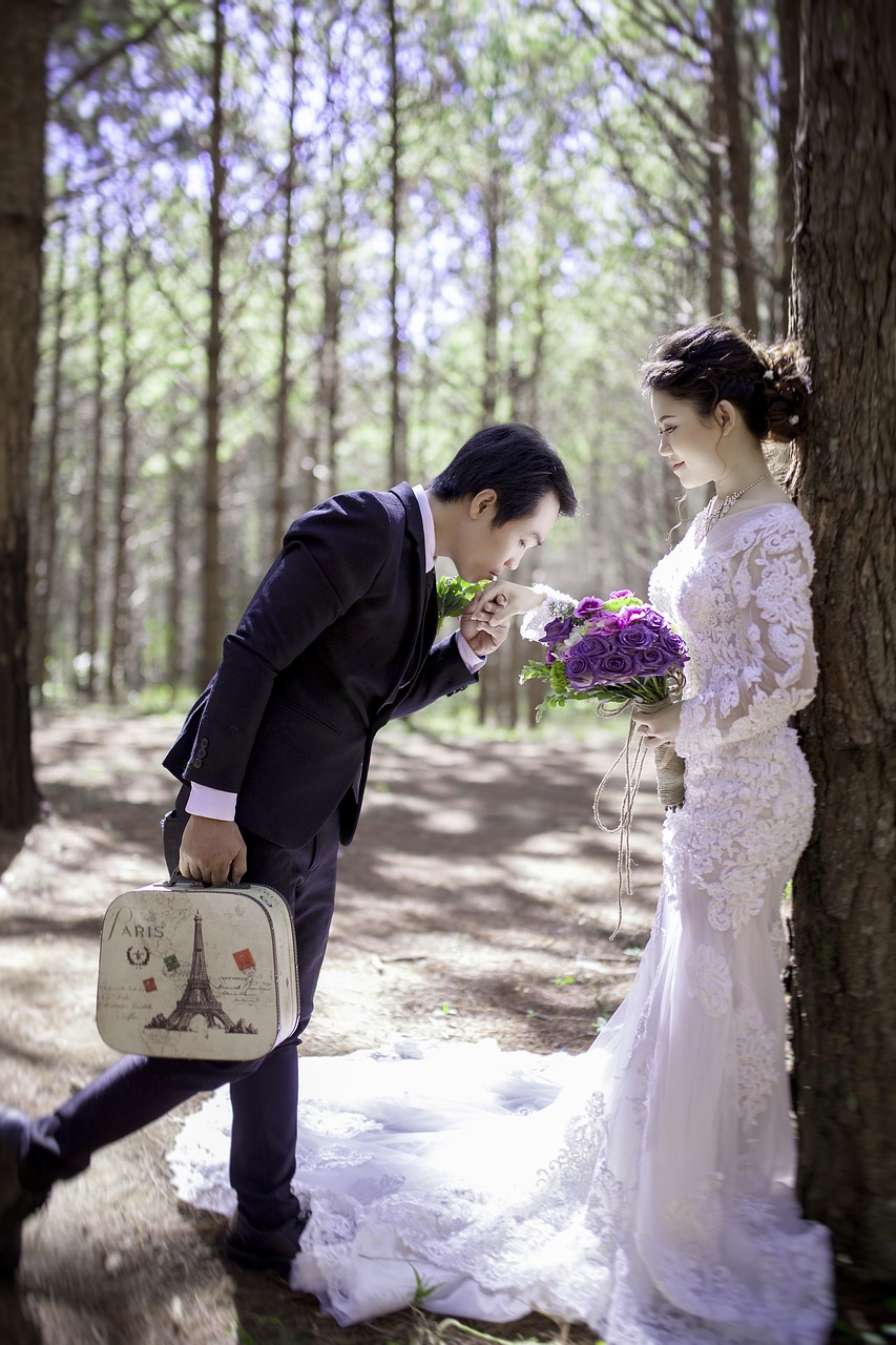 Groom kissing bride's hand in the woods